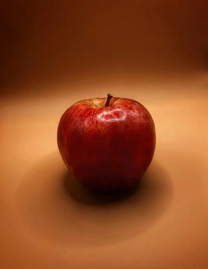 A whole apple beside a jug of apple cider vinegar
