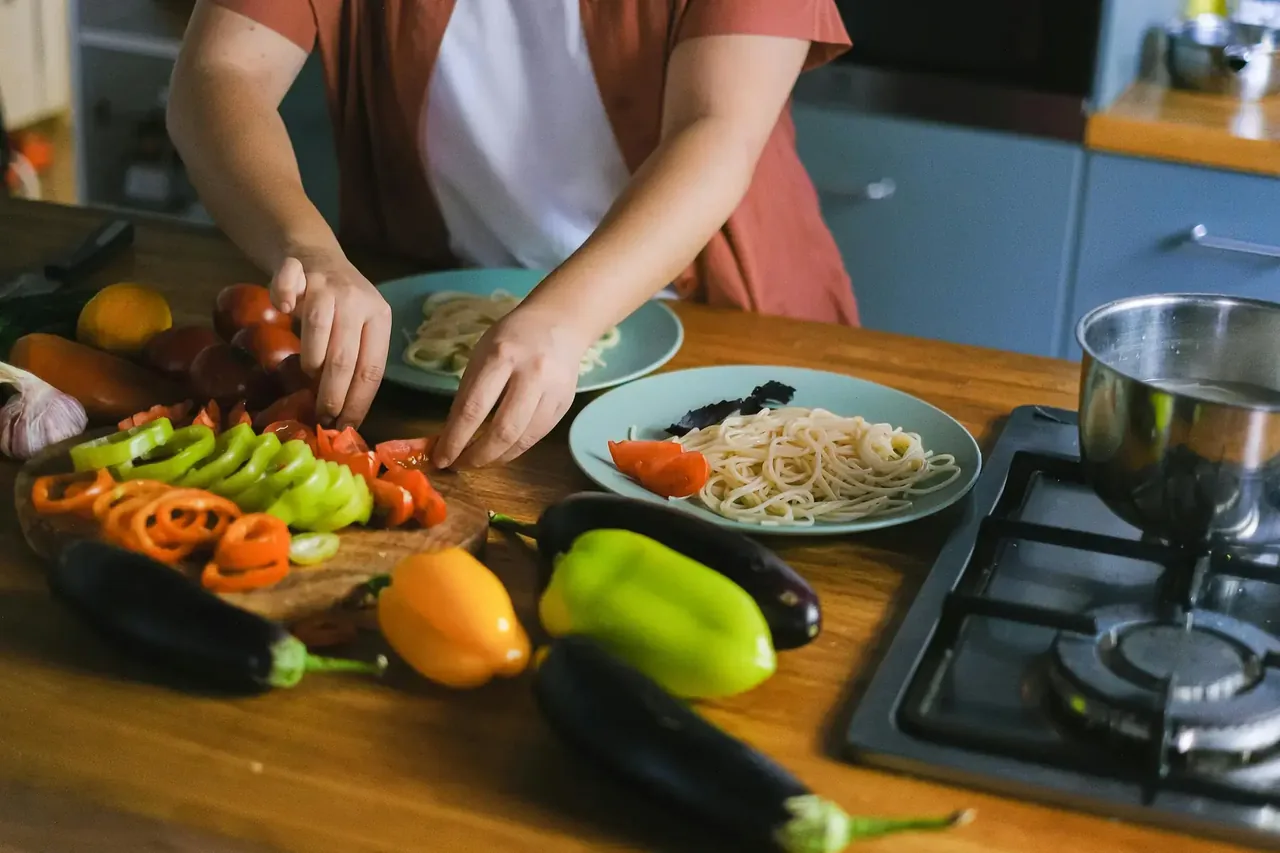 Someone chopping vegetables at a kitchen counter with a pan on the stove